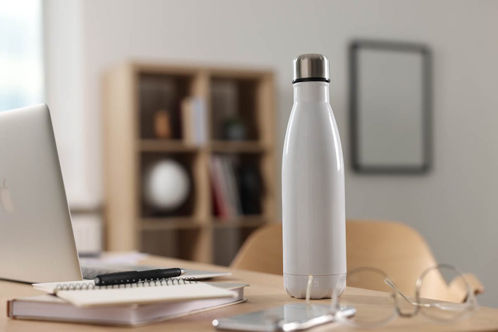 White thermos bottle on wooden table indoors.