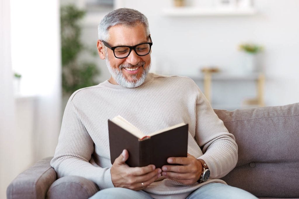 happy senior man reading a book on his couch