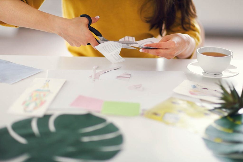 a woman creating a vision board. Cutting paper with sissors.