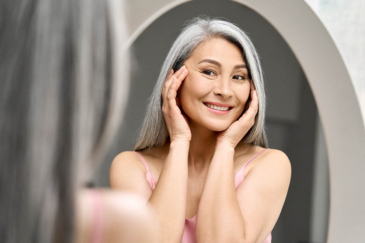 happy middle age mature woman smiling into the mirror