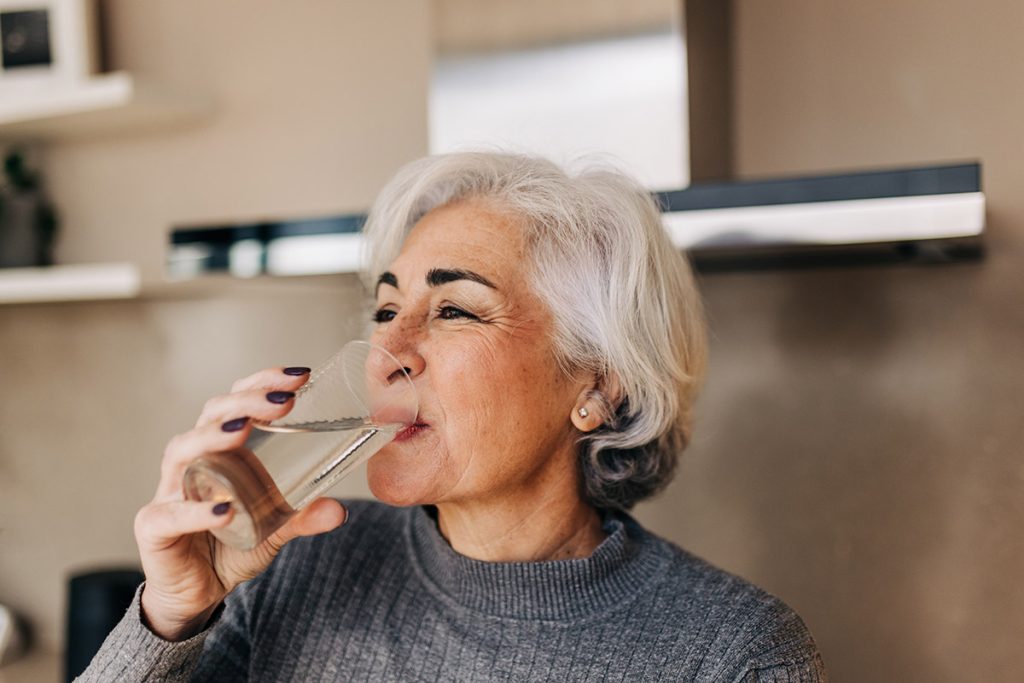 Mature woman drinking fresh clean water from a glass. 
