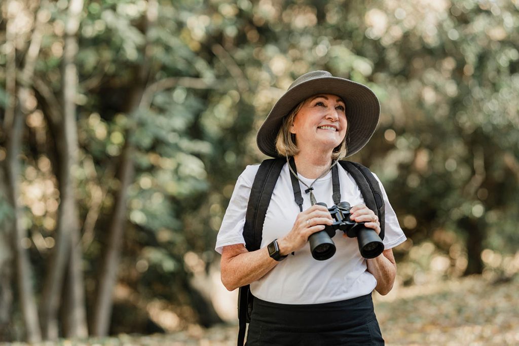 Active senior woman using binoculars to see the beauty of nature