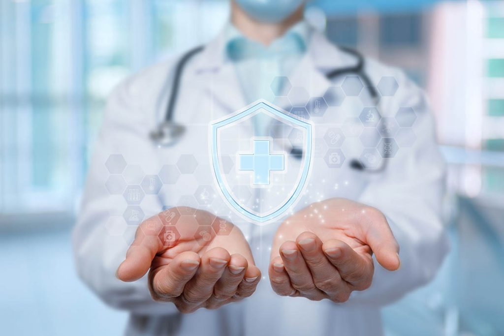 Doctor shows health protection symbol on blurred background.