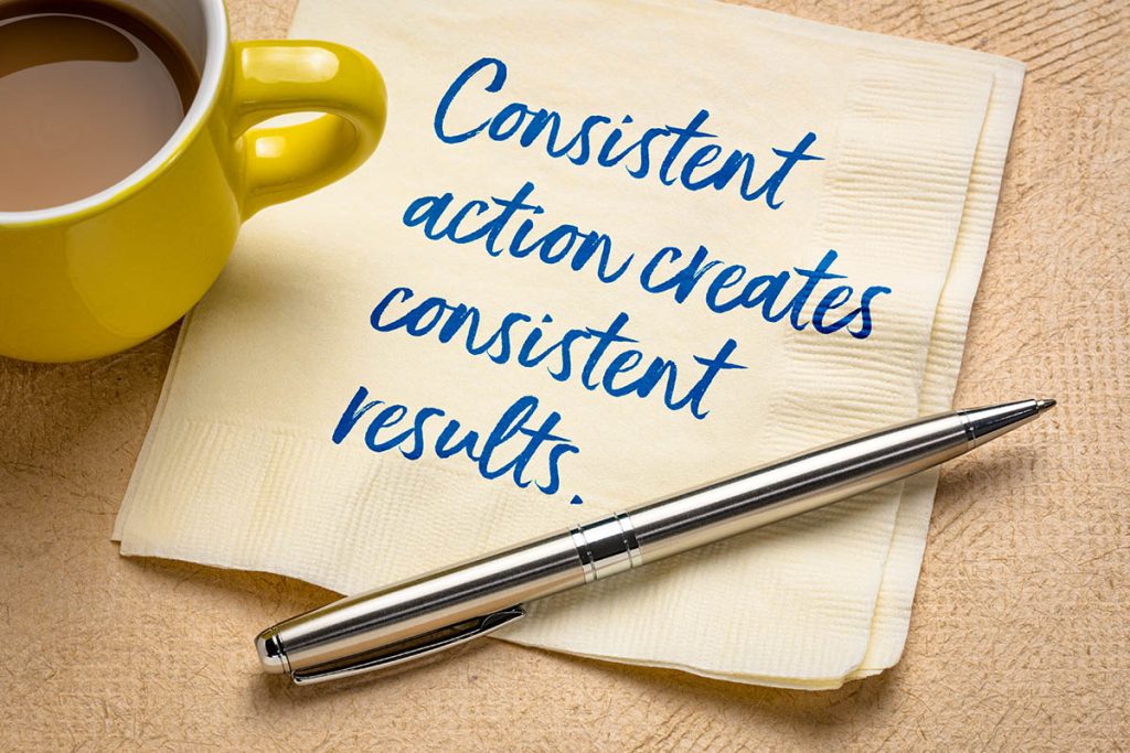 Consistent action creates consistent results - handwriting on a napkin with a cup of coffee