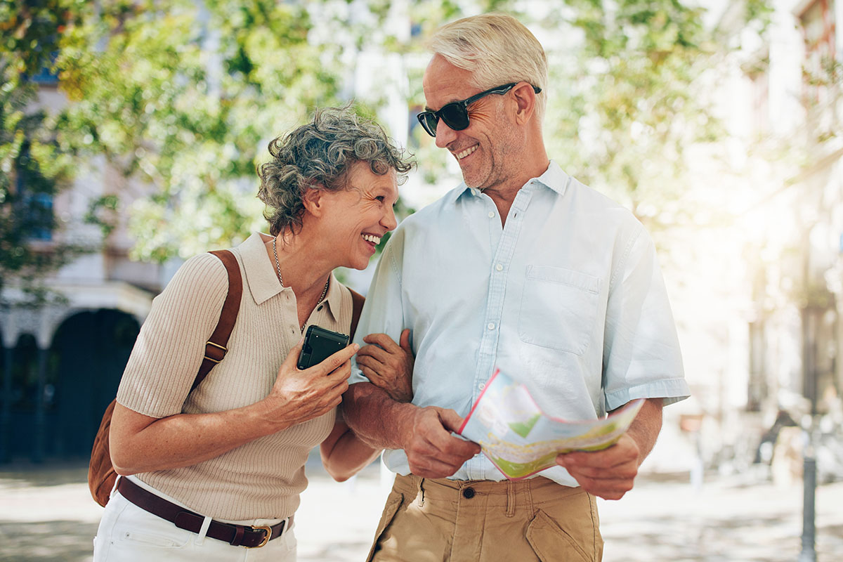 Retired couple walking around the town with a map. Smiling mature man and woman roaming around the city.