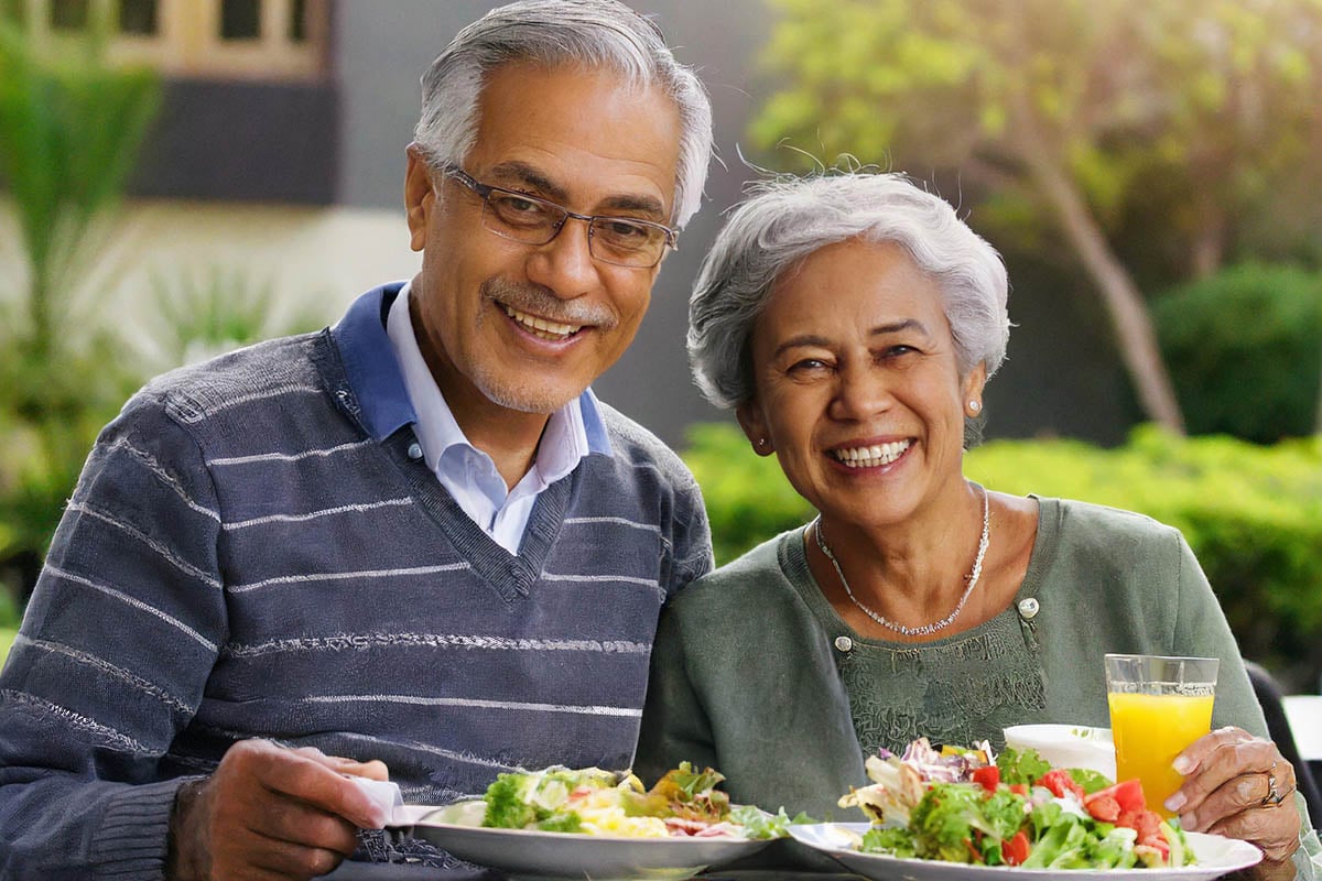 older couple smiling with a plate of salad