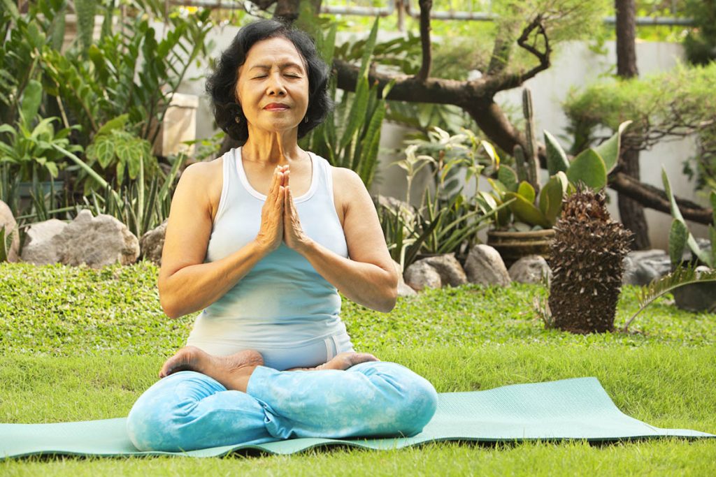 Senior woman meditating as part of yoga training