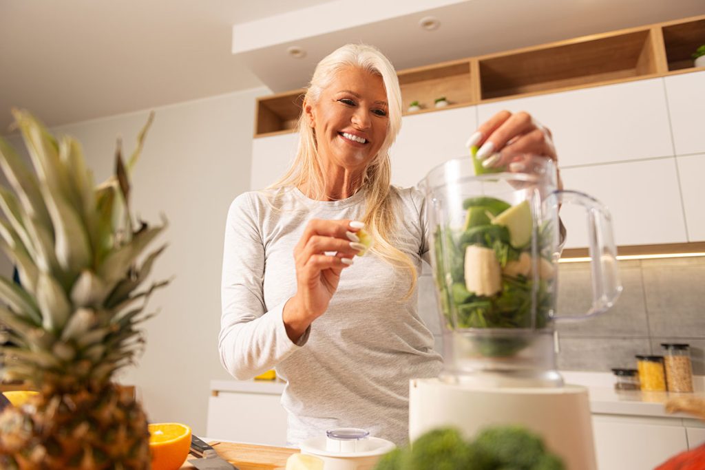 woman preparing healthy and delicious green smoothie in a modern kitchen