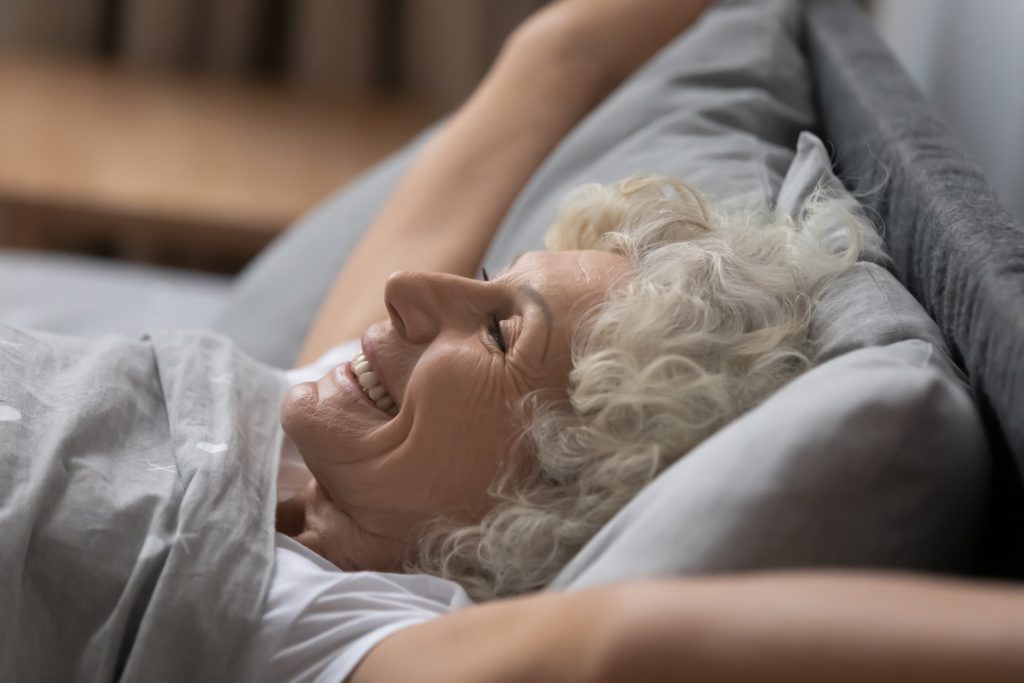 older woman happy stretching in bed