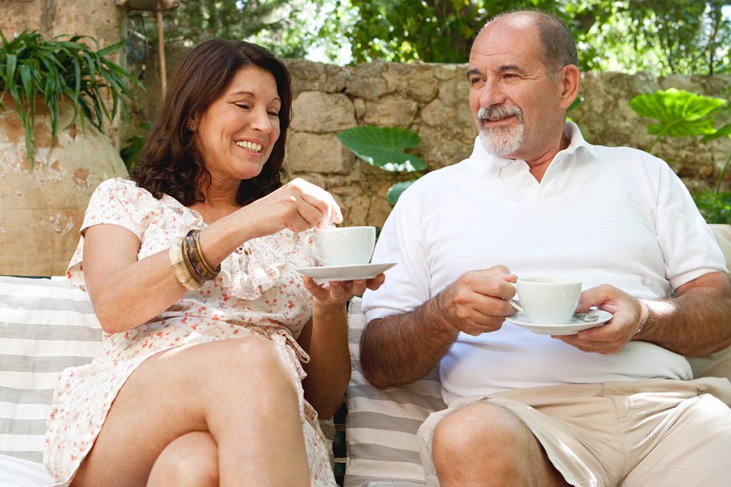 older couple sitting outdoors drinking from a mug together