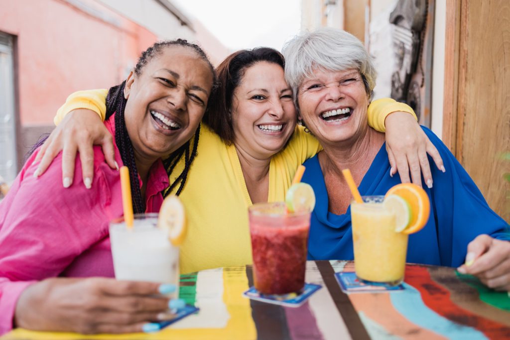 Diverse group of older friends smiling over drinks together