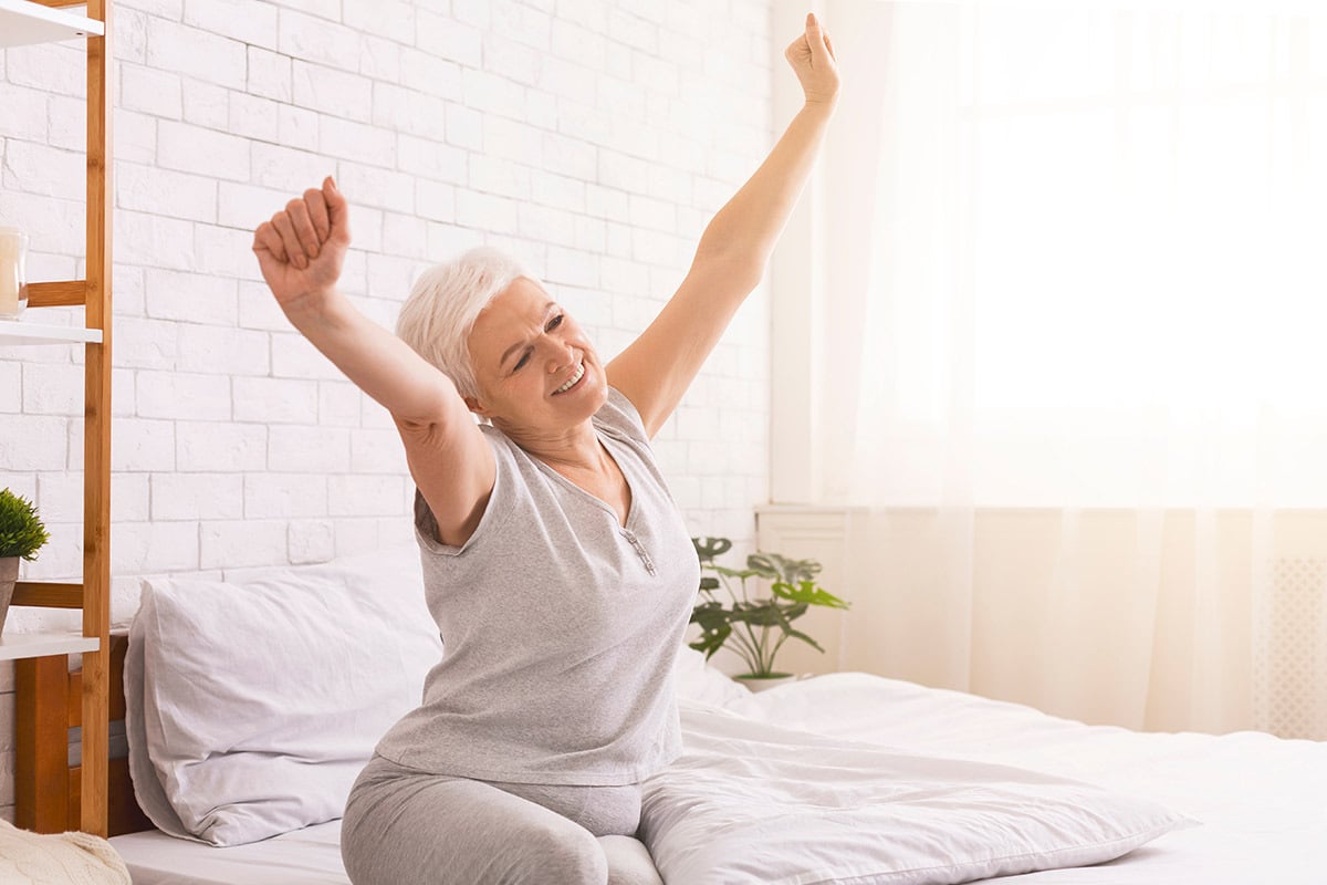 mature woman stretching and waking up from bed