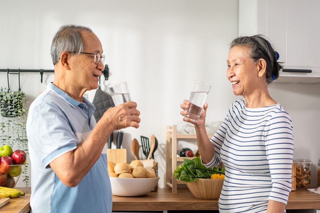 senior elderly couple drink a glass of water in kitchen at home. Mature older thirsty grandparent holding clean mineral natural in cup after waking up and sip in morning for health care in house