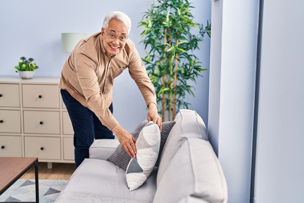 Senior man smiling confident organize sofa at home