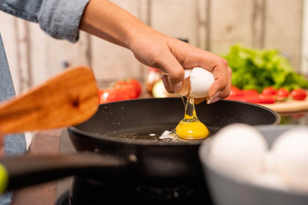fresh egg on frying pan standing on electric stove while cooking breakfast in the morning