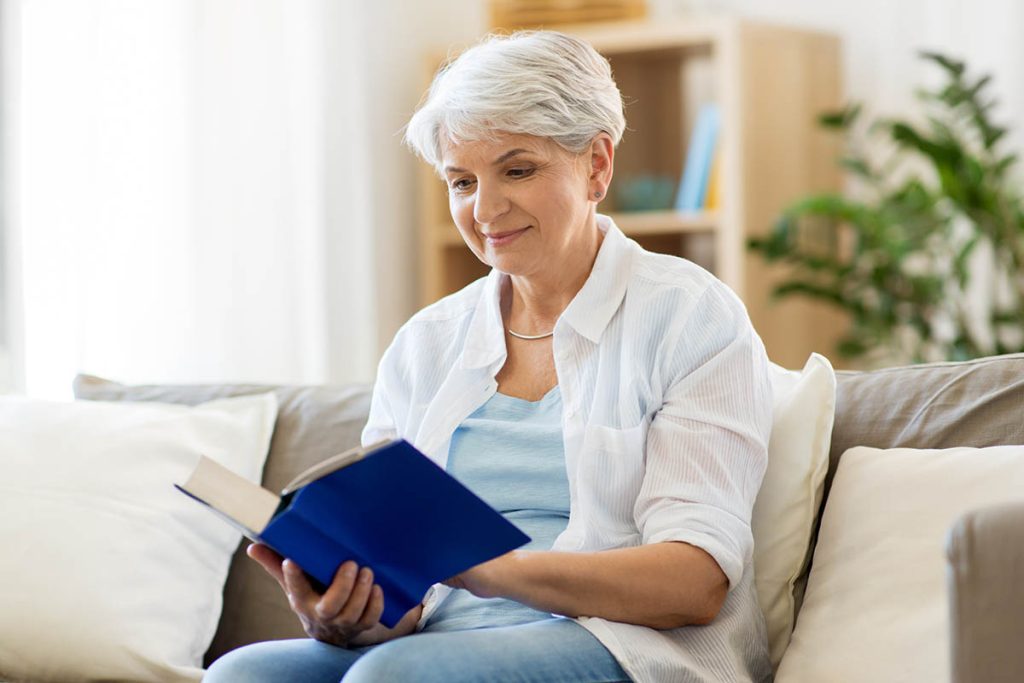 happy smiling senior woman reading book at home